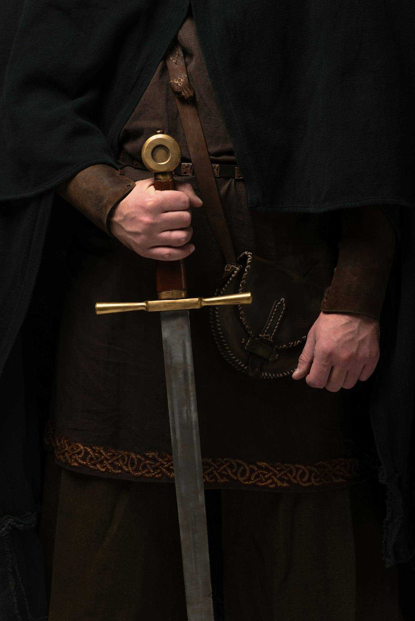 cropped view of medieval Scottish knight in mantel with sword